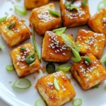 - 1 block firm tofu (14 oz), pressed and cubed - ½ cup cornstarch - 3 tablespoons vegetable oil - 4 cloves garlic, minced - ¼ cup sweet chili sauce - 2 tablespoons soy sauce - 1 tablespoon rice vinegar - 1 teaspoon sesame oil - 1 green onion, thinly sliced (for garnish) - Sesame seeds (for garnish) Tofu is the star of this dish. It’s made from soybeans and is a great source of protein. Firm tofu holds its shape well during cooking. Pressing the tofu helps remove water. This step makes it crispier when cooked. Tofu easily absorbs flavors, making it perfect for sweet chili sauce. It’s a versatile ingredient that fits into many diets. Garnishes add a nice touch to the dish. I suggest using thinly sliced green onions. They bring a fresh flavor and a pop of color. Sesame seeds are another great choice. They add a crunchy texture and nutty taste. For an extra burst of color, add fresh cilantro around the dish. These garnishes make your Sweet Chili Garlic Tofu Bites look inviting and appealing! To start, we need to press the tofu. This helps get rid of extra moisture. Wrap the tofu in a clean towel. Place a heavy object on top, like a skillet. Let it sit for 15 to 20 minutes. This step is important for crispy bites. After pressing, cut the tofu into small cubes. Aim for about one-inch pieces. These will cook evenly and become crunchy. Next, we’ll coat the tofu for crispiness. In a bowl, add cornstarch and the tofu cubes. Toss them gently until each piece is covered. This coating creates a crunchy texture when we fry them. Heat a non-stick skillet over medium-high heat. Add vegetable oil and let it heat until it shimmers. Carefully place the coated tofu cubes in a single layer. Cook for 4 to 5 minutes on each side. Look for a golden brown color. Once they’re crispy, take them out and set them aside on a plate. Now, let’s make the sweet chili sauce. In the same skillet, reduce the heat to medium. Add minced garlic and sauté for about 30 seconds. Stir it well but don’t let it burn. Next, pour in sweet chili sauce, soy sauce, rice vinegar, and sesame oil. Mix everything together and let it simmer. This brings all the flavors together. After that, return the crispy tofu to the skillet. Toss the tofu until it’s well coated in the sauce. Cook for another 2 to 3 minutes. This step warms everything through and blends the flavors nicely. To get that perfect crunch, start with firm tofu. Press the tofu well to remove moisture. Wrap it in a clean towel and put a heavy object on top. After 15-20 minutes, cut the tofu into cubes. Toss the cubes in cornstarch. This makes them crispy when cooked. Cook them in hot oil for 4-5 minutes on each side. Golden brown is the goal! To boost the flavor, think about your sauces. Sweet chili sauce is great, but you can add more. Try garlic powder or chili flakes for extra kick. Adding a splash of lime juice brightens the dish. You can also mix in fresh herbs for freshness, like cilantro or basil. Each bite should be packed with flavor! For serving, presentation matters. Place the tofu bites on a nice platter. Drizzle any extra sauce on top. Garnish with green onions and sesame seeds for color. Serve with rice or a fresh salad. You can also pair them with dipping sauces like soy sauce or sriracha. Enjoy your crunchy treat with friends or family! {{image_4}} You can change the sauce for a new taste. Try a spicy peanut sauce. This sauce adds a different kick and richness. You may also use teriyaki sauce for a sweet and savory mix. Feel free to mix ingredients. Add lime juice for a zesty twist. Each option lets you play with flavors! Adding veggies makes this dish even better. You can toss in bell peppers, snap peas, or broccoli. These colorful options add crunch and nutrition. If you want more protein, try adding chickpeas or edamame. Simply sauté them with the tofu. This way, you make a more filling meal. This recipe is already vegan, which is great! To keep it gluten-free, use tamari instead of soy sauce. Check your sweet chili sauce for gluten too. Some brands add wheat. You can make this dish fit many diets without losing taste. Enjoy these tasty bites without worry! Tofu bites need proper storage to keep them fresh. First, let them cool completely. Place the bites in an airtight container. You should cover the container to prevent air from getting in. Store the container in the fridge. They last for about 3-4 days this way. If you want to keep them longer, freezing is your best option. Reheating your tofu bites is easy. Use a skillet for the best results. Heat the skillet over medium heat. Add a little oil to help them crisp up again. Place the tofu bites in the skillet and heat for about 5-7 minutes. Flip them halfway through so they warm evenly. You can also use an oven. Preheat it to 350°F (175°C). Spread the tofu bites on a baking sheet and heat for 10-15 minutes. Freezing tofu bites is a great way to save leftovers. First, let them cool completely. Then, arrange the bites in a single layer on a baking sheet. Freeze them for about 1-2 hours until firm. After that, transfer the frozen bites to a freezer-safe bag. Remove as much air as possible before sealing. They can stay in the freezer for up to 3 months. When you're ready to eat, thaw them in the fridge overnight before reheating. To press tofu, wrap it in a clean kitchen towel. Place a heavy object on top, like a cast-iron skillet. Let it sit for 15-20 minutes. This helps remove extra moisture. Dry tofu absorbs flavors better and gets crispier when cooked. Yes, you can switch up the sauces! Try teriyaki for a sweet twist. You can also use sriracha for heat. Mixing soy sauce with honey gives a nice flavor too. Get creative and find what you love. These tofu bites last about 3-4 days in the fridge. Store them in an airtight container to keep them fresh. Reheat them in a skillet for best results. They may lose some crunch when microwaved. Serve these tofu bites with rice or quinoa for a complete meal. They pair well with steamed vegetables or a fresh salad. For a fun twist, try them in lettuce wraps. They make a great appetizer too! In this blog post, we explored how to make delicious Sweet Chili Garlic Tofu Bites. We detailed the key ingredients, like tofu and tasty sauces. I shared tips for getting your tofu crispy and highlighted variations to suit your taste. Proper storage methods help you keep leftovers fresh, too. Tofu can be a great addition to any meal. With these steps, you can enjoy this dish any time. Keep experimenting and make it your own!